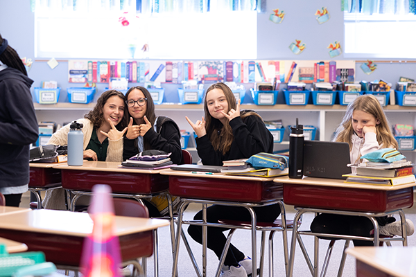 girls smiling at desks in classroom