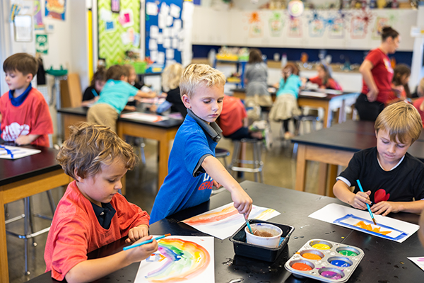 students painting at table in classroom