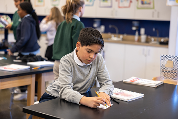 male student sitting and writing at desk