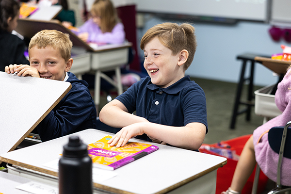 two boys sitting at desks in classroom