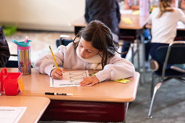 girl writing at desk in classroom