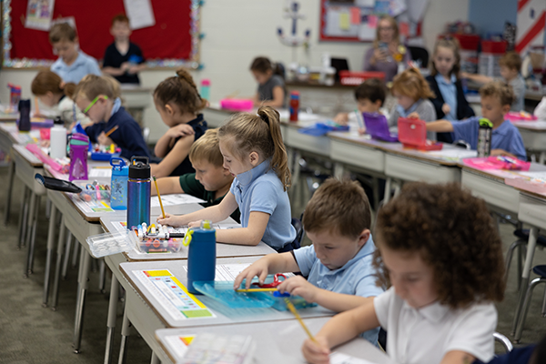 young students writing at desks in classroom